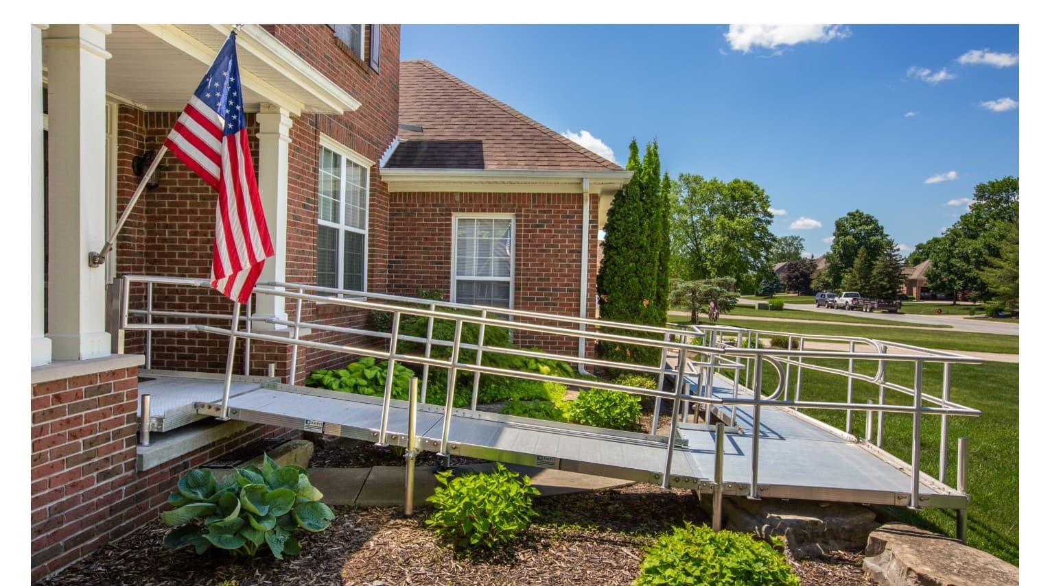 Rampit USA aluminum wheelchair ramp installed at a brick residential home with American flag